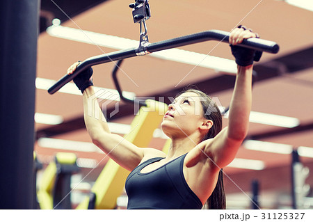 woman flexing arm muscles on cable machine in gym woman flexing arm muscles on cable machine in gym 31125327