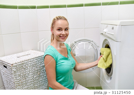 happy woman putting laundry into washer at home happy woman putting laundry into washer at home 31125450