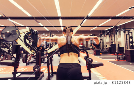 woman flexing muscles on cable machine in gym 31125843
