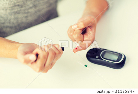 close up of woman making blood test by glucometer close up of woman making blood test by glucometer 31125847