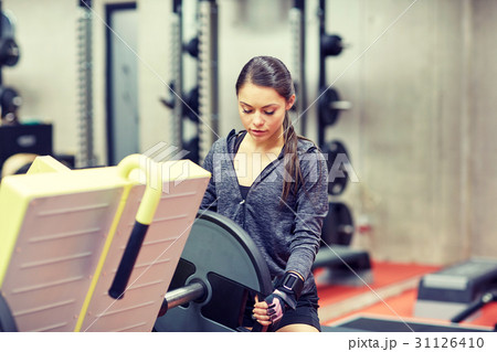 young woman adjusting leg press machine in gym 31126410