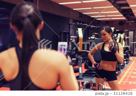 woman with smartphone taking mirror selfie in gym 31126416