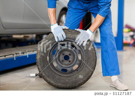mechanic with wheel tire at car workshop 31127187