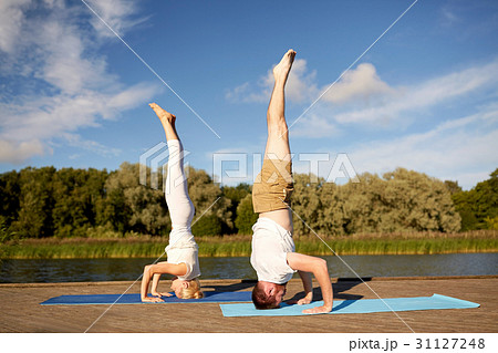 couple making yoga headstand on mat outdoors 31127248