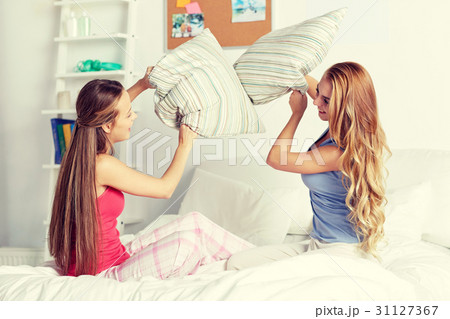 happy teen girl friends fighting pillows at home 31127367