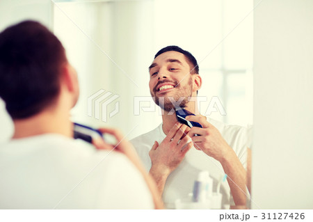 man shaving beard with trimmer at bathroom 31127426