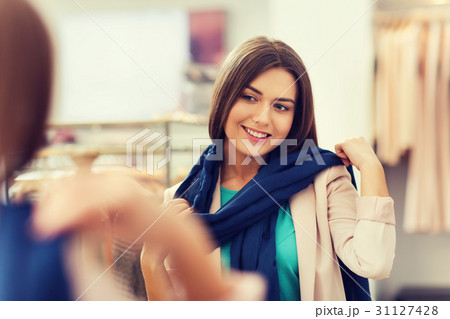 happy woman posing at mirror in clothing store 31127428