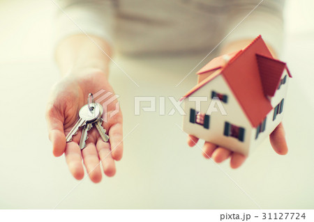 close up of hands holding house model and keys 31127724