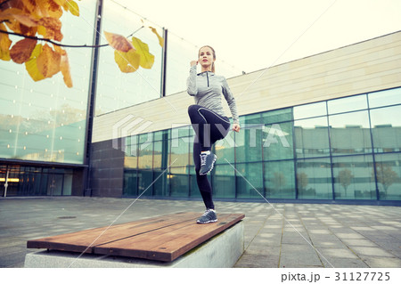 woman making step exercise on city street bench 31127725