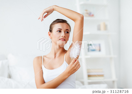 woman with feather touching her armpit at home 31128716