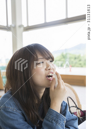 大学のカフェスペースで喉スプレーをする女子大生 撮影協力 日本経済大学の写真素材