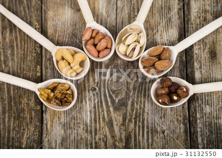Nuts in a wooden spoons on a  wooden table. 31132550
