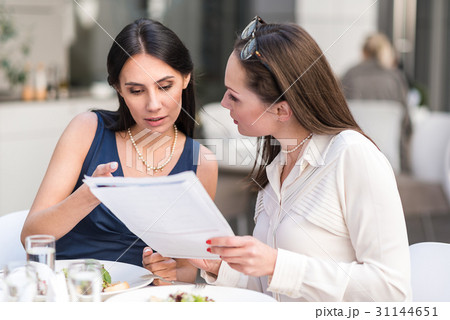 Composed females arguing paper in cafe 31144651