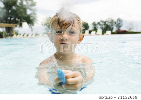 Boy (6-7) playing with squirt gun in swimming pool Boy (6-7) playing with squirt gun in swimming pool 31152659