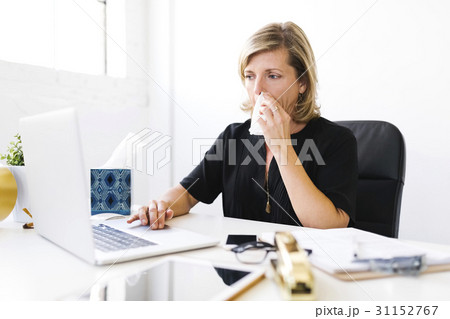 Woman using laptop, blowing nose Woman using laptop, blowing nose 31152767