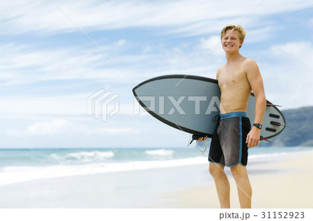 Man standing on beach and holding surfboard 31152923