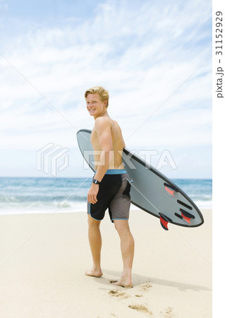 Man walking on beach and holding surfboard 31152929