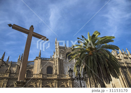 Spain, Andalusia, Seville, Cathedral of Seville with palm tree and cross in foreground 31153170