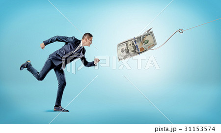 A businessman running after a dollar bill that's A businessman running after a dollar bill that's 31153574