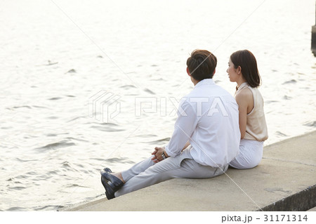a couple is sitting on the river bank. 31171314
