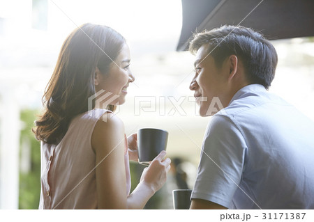 a woman is holding a cup and smiling at her boyfriend in the café. 31171387