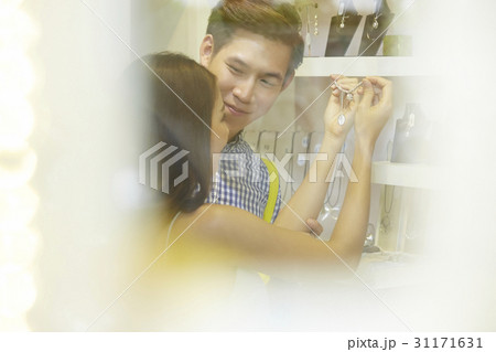 a man is looking a woman holding and looking a necklace in a shop a man is looking a woman holding and looking a necklace in a shop 31171631