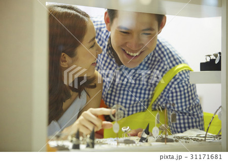 a girl is smiling and pointing to the items on shelf for a man a girl is smiling and pointing to the items on shelf for a man 31171681