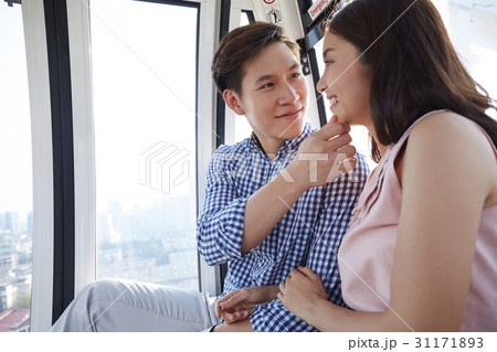 A man is touching his girlfriend's chin on a cable car. A man is touching his girlfriend's chin on a cable car. 31171893