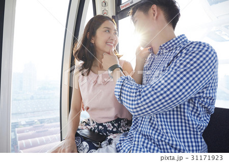 An Asian couple is touching each other's chin on a cable car. 31171923