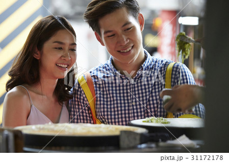 a couple is happily looking at someone making food a couple is happily looking at someone making food 31172178
