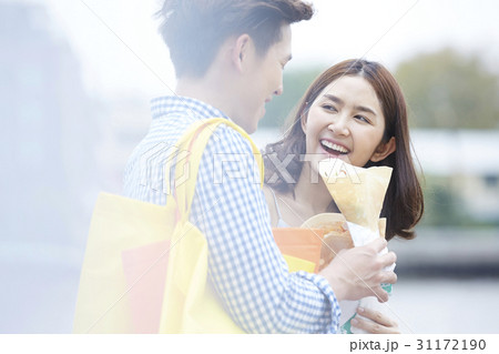 woman smiles and looks at man carrying bags and holding food 31172190