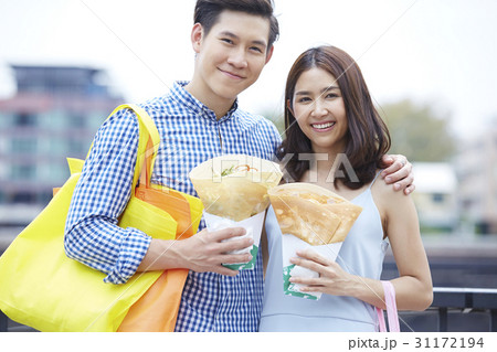 a portrait of a happy couple carrying bag, smiling and holding food a portrait of a happy couple carrying bag, smiling and holding food 31172194