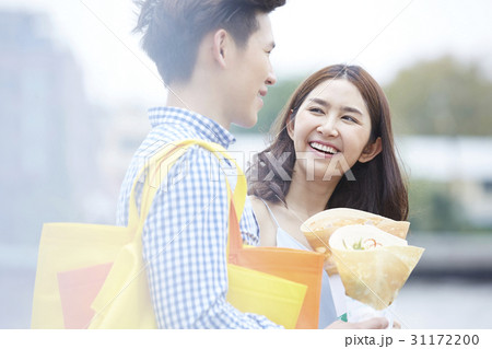 a couple is holding food, smiling and talking happily a couple is holding food, smiling and talking happily 31172200