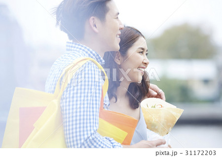 woman is in man's arm, holding food, smiling and looking at something 31172203