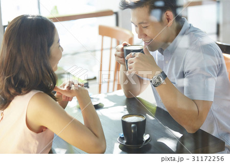 a man drinks coffee, smiles and talks to a woman in a coffee shop 31172256