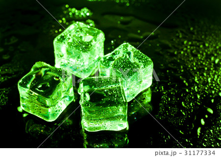 Green ice cubes on black wet table. 31177334