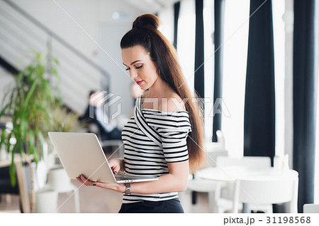 Charming female is using mobile phone and laptop Charming female is using mobile phone and laptop 31198568