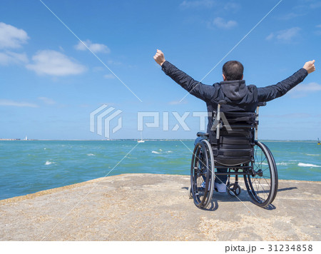 Disabled young man sitting in a wheelchair and looks at the sea 31234858