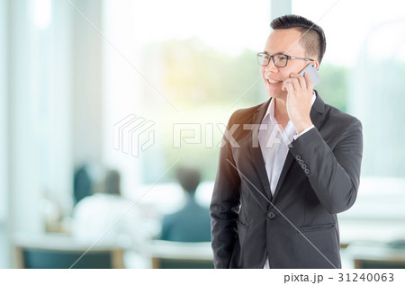Handsome businessman using smart phone in office Handsome businessman using smart phone in office 31240063
