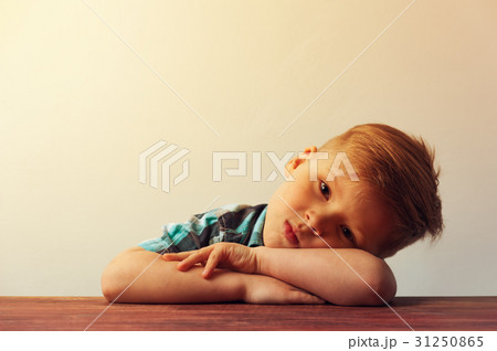 Pensive sad child sitting at the table 31250865