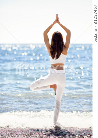 Young woman doing yoga in the beach wearing white clothes Young woman doing yoga in the beach wearing white clothes 31257467