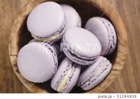 violet macarons in wood bowl on wooden table 31264939