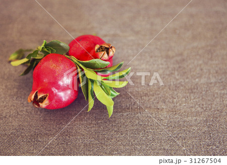 Two pomegranate fruits on textile background Two pomegranate fruits on textile background 31267504
