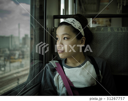 電車の窓から景色を眺める女性の写真素材