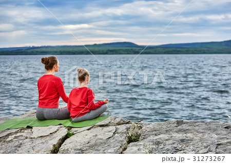 Rear view of mother and daughter practicing yoga 31273267
