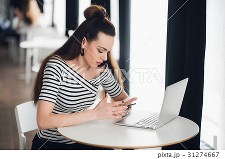 Young woman is sitting in a cafe and working 31274667