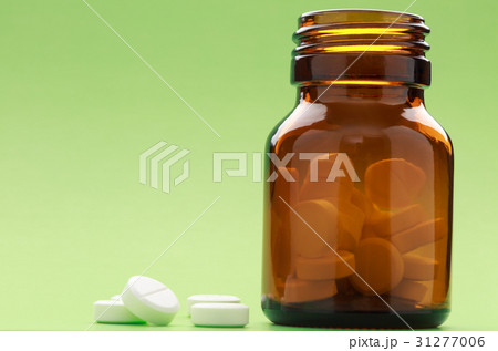 A bottle of brown-glass pills on a green 31277006