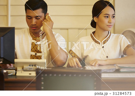 male receptionist talks on phone and the female looks at something male receptionist talks on phone and the female looks at something 31284573