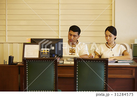 two receptionists are working in reception desk. two receptionists are working in reception desk. 31284575