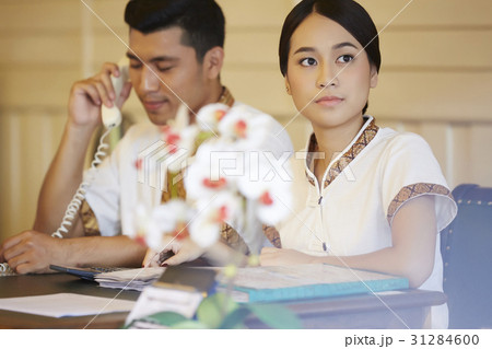 the receptionist is looking outside when her colleague is calling. 31284600